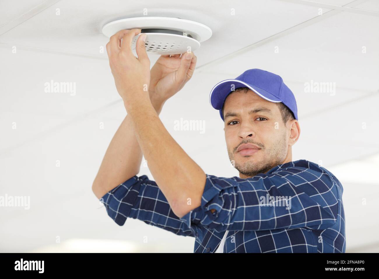male technician installing ceiling fan Stock Photo