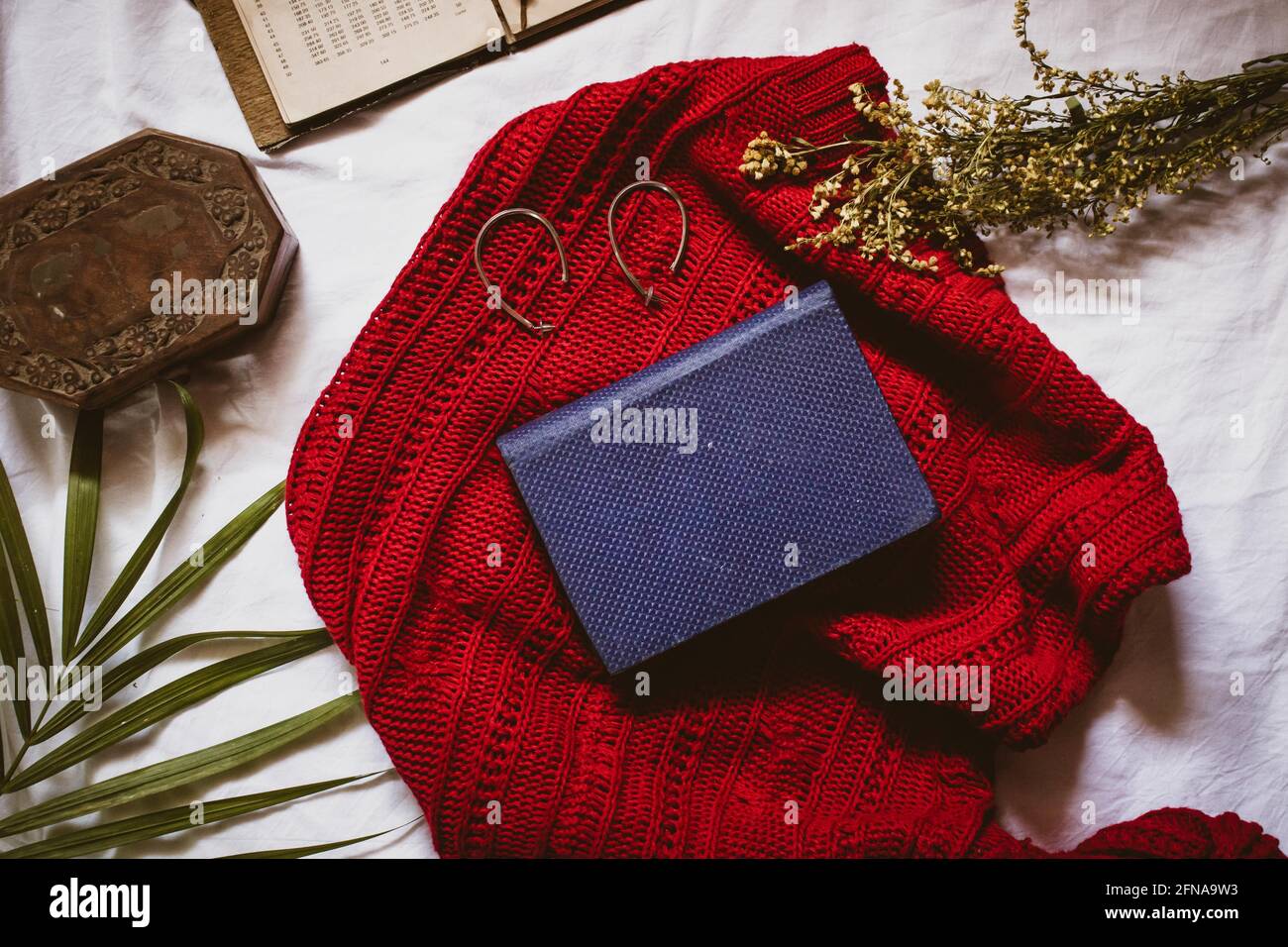 Hardcover diary with blue binding on a red sweater with earrings and jewelry box around it Stock Photo