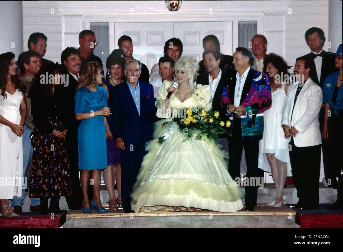 Branson entertainers gather at the Dixie Stampede on opening night July 17th, 1995 to welcome Dolly Parton (yellow dress) as the newest venue in the country music town. Some of the top names include Andy Williams and Tony Orlando (left of Parton), and Charley Pride (behind Parton). In January 2018, the company dropped the word, “Dixie” from the title due to cultural concerns. The Civil War themed dinner show featured horseback trick riding in an arena while patrons watched and ate dinner. Stock Photo