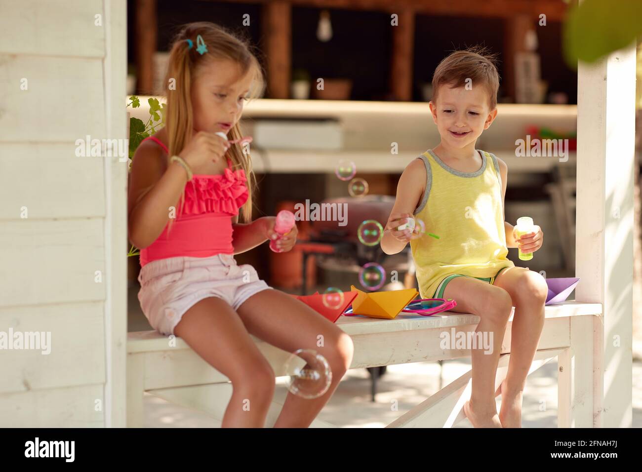 cute little girl teaching her brother how to make soap bubbles Stock Photo