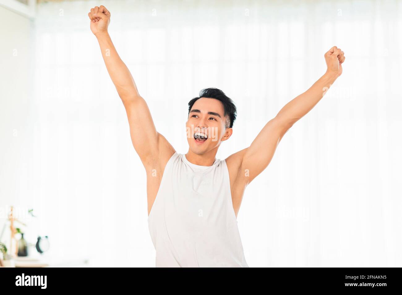 Happy Asian young man Doing Exercises at Home Stock Photo