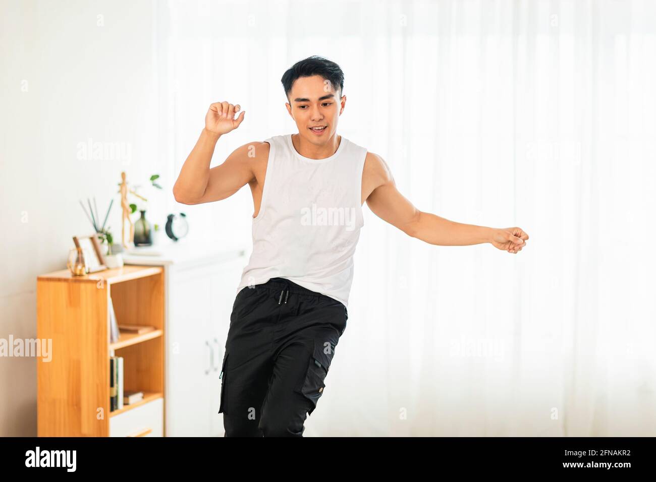 Happy Asian young man Doing Exercises and dancing at Home Stock Photo