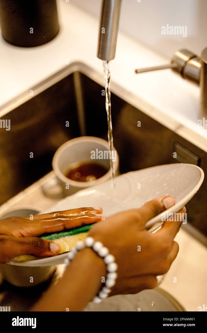 Woman's hands washing dish with scourer and tap water Stock Photo Alamy