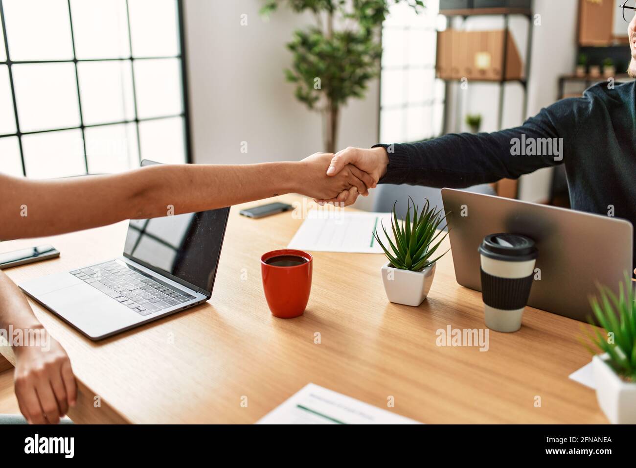 Two business arms shaking hands at the office Stock Photo Alamy