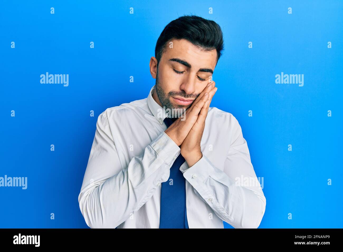 Young hispanic man wearing business clothes sleeping tired dreaming and ...