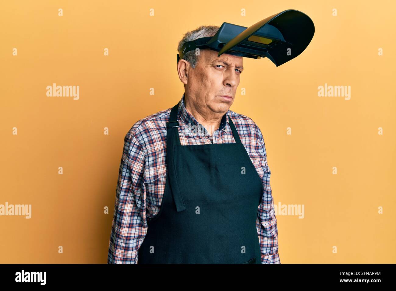 Handsome senior man with grey hair wearing welding protection mask depressed and worry for distress, crying angry and afraid. sad expression. Stock Photo