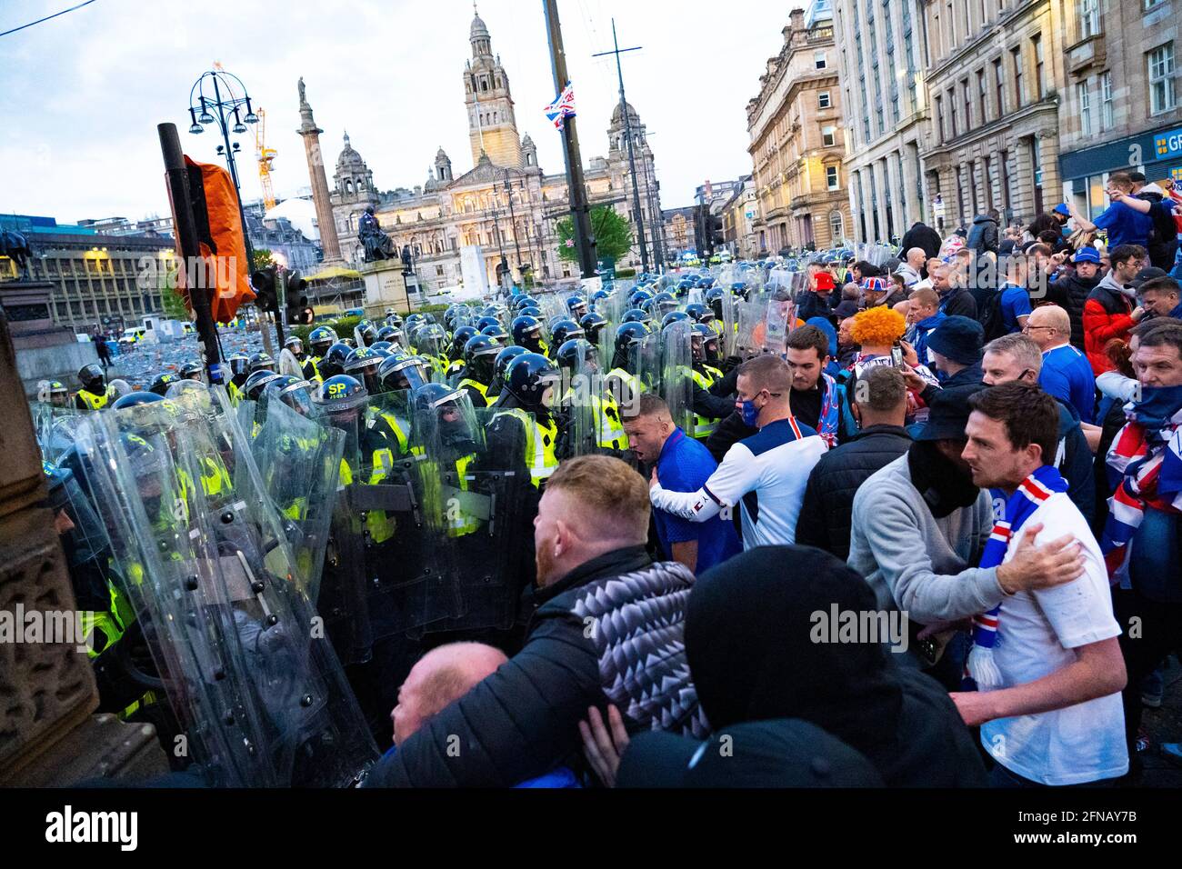 Glasgow, Scotland, UK. 15 May 202. Rangers football supporters  celebrating 55th league victory are cleared from George Square by police in riot gear on Saturday evening. In very violent scenes police were pelted with bottles and items from a nearby construction site as police pushed the supporters into the south west corner of the square. Pic; Violent clashes between police and fans.  Iain Masterton/Alamy Live News. Stock Photo