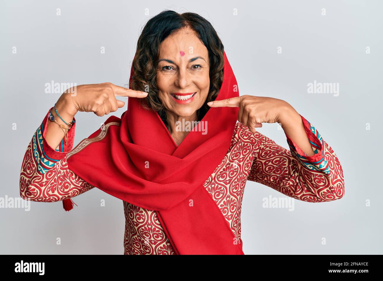 Middle age hispanic woman wearing tradition sherwani saree clothes smiling cheerful showing and pointing with fingers teeth and mouth. dental health c Stock Photo