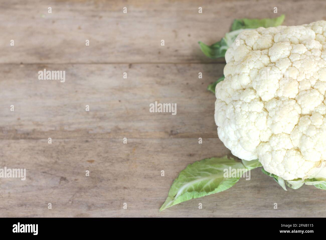 White cauliflower was placed on a wooden floor, leaving space for text messages. Stock Photo