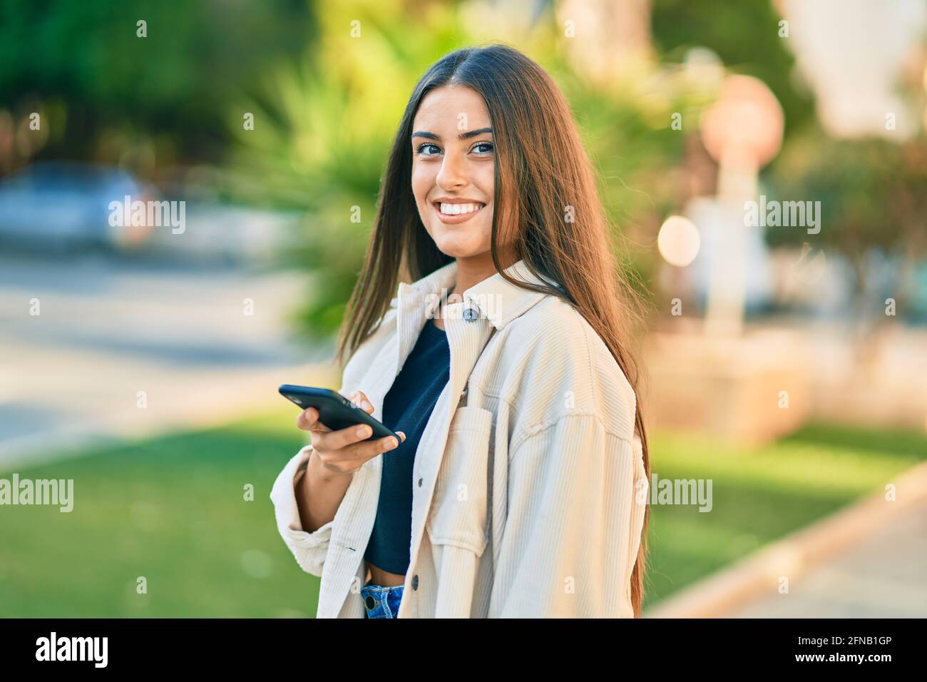 Young hispanic girl smiling happy using smartphone at the park Stock ...