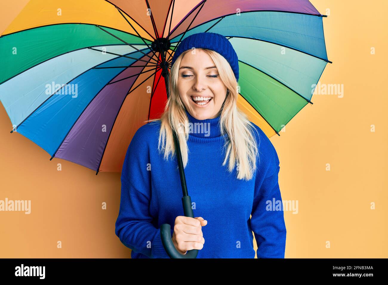 Young caucasian woman holding colorful umbrella smiling and laughing hard  out loud because funny crazy joke Stock Photo - Alamy