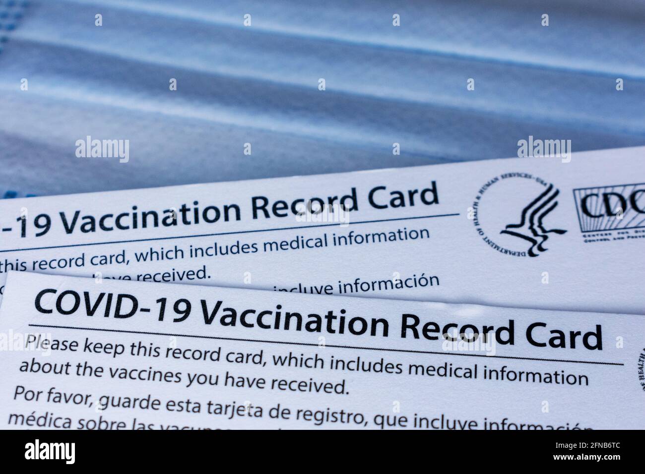 Closeup. Covid-19 vaccination record cards issued by CDC, United States Centers for Disease Control and Prevention, on a blue disposable protective fa Stock Photo