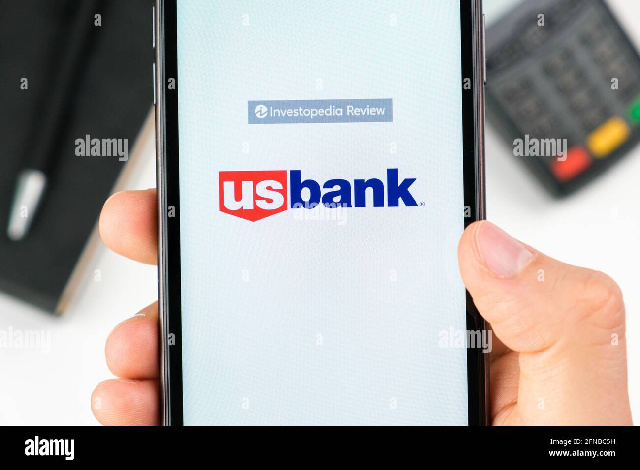 US bank logo on the smartphone screen in mans hand on the background of payment terminal, May 2021, San Francisco, USA Stock Photo