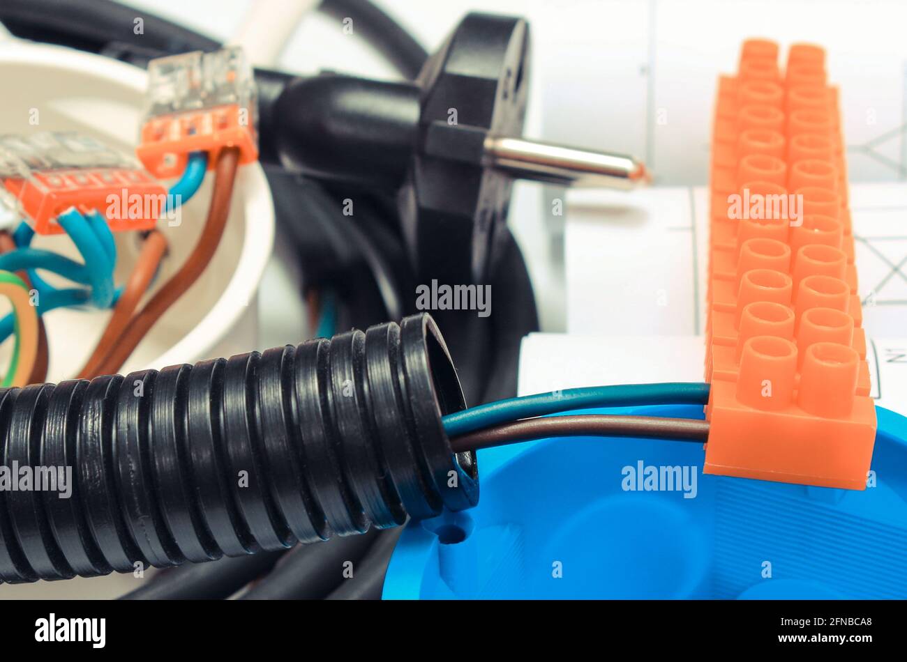 Electrical box, plug and cube with connected electric copper wires and construction drawings of house. Components and accessories for electrical insta Stock Photo