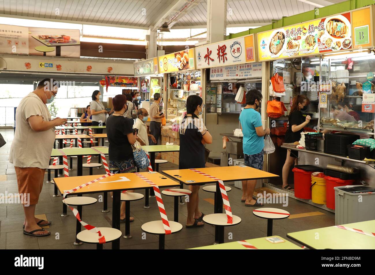 Singapore, Singapore. 16th May, 2021. People queue up at a hawker center as  tables are cordoned off as no dining-in is allowed.Tightened COVID-19  measures known as Phase 2 (Heightened Alert) starts from