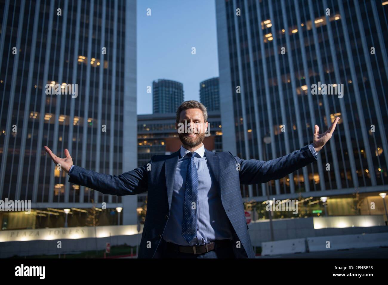Businessman raising arms near cityscape office building. Happy, success ...