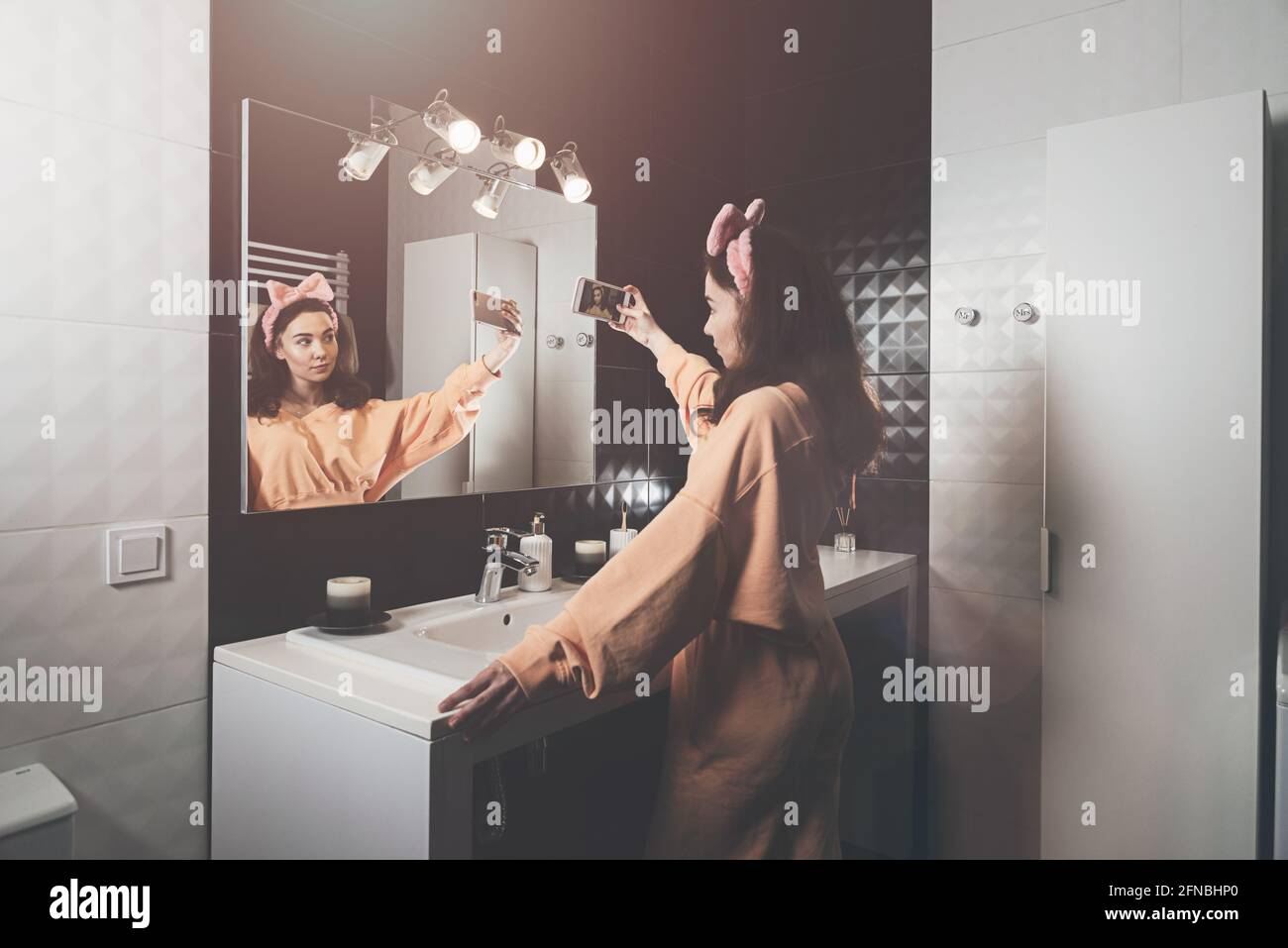 Portrait view of beautiful young woman making selfie in home bathroom. mirror face reflection ...