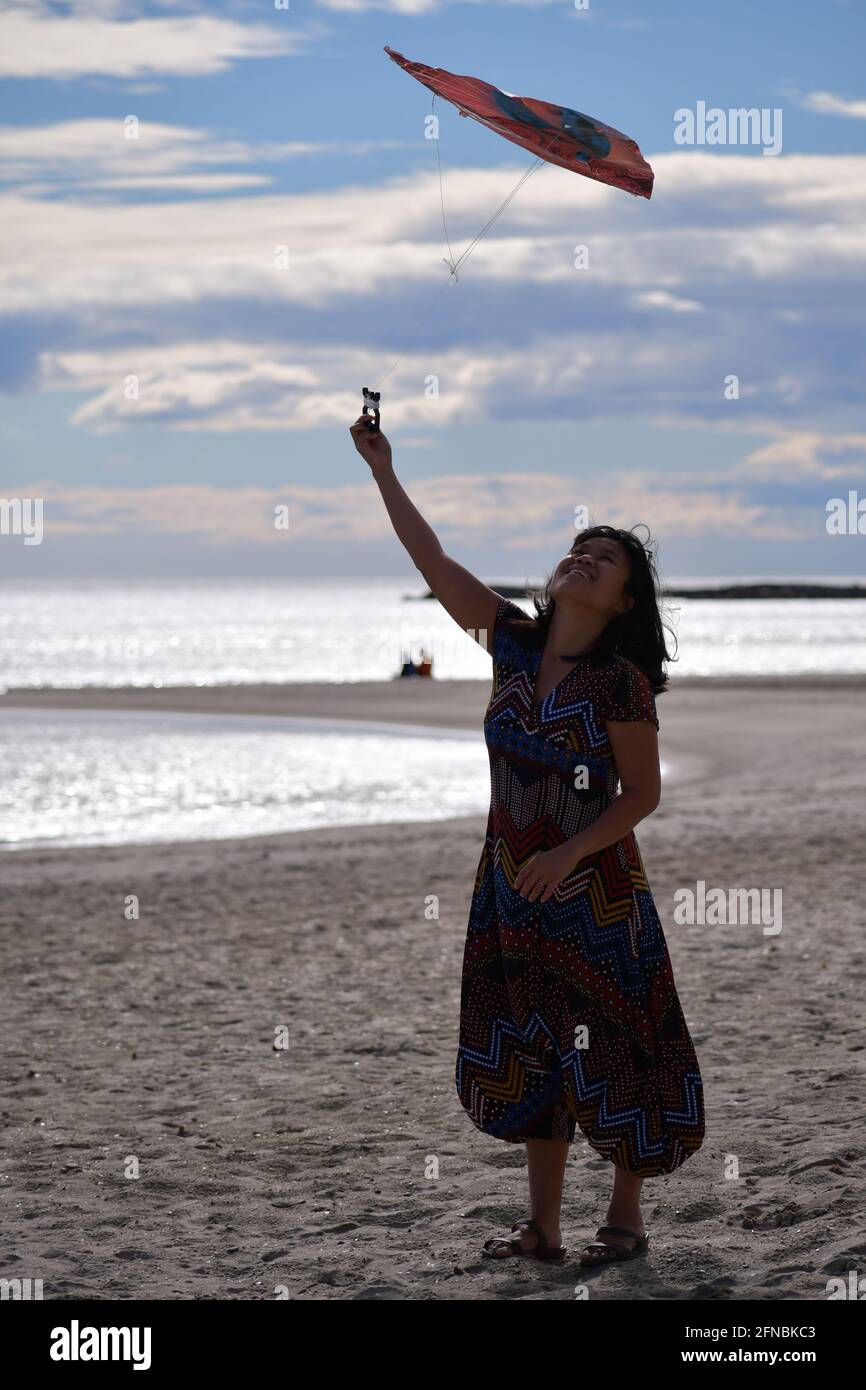 Asian Filipino woman flying a kite during Kite Festival in Palavas les Flots, Carnon Plage, Montpellier, Occitanie, South of France, Sud de France Stock Photo