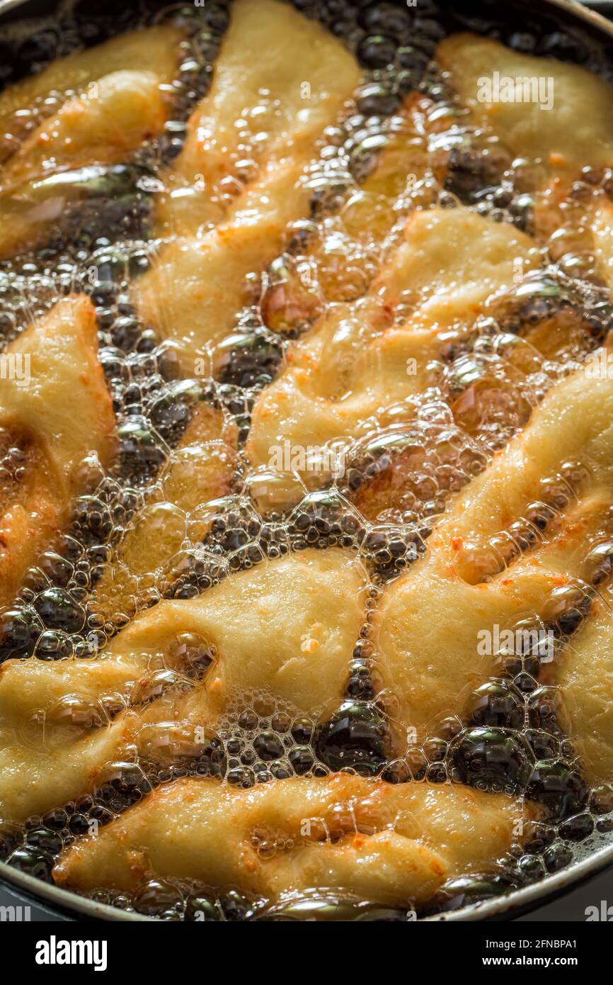 Frying delicious angel wings on hot oil. Homemade pastries. Donuts for