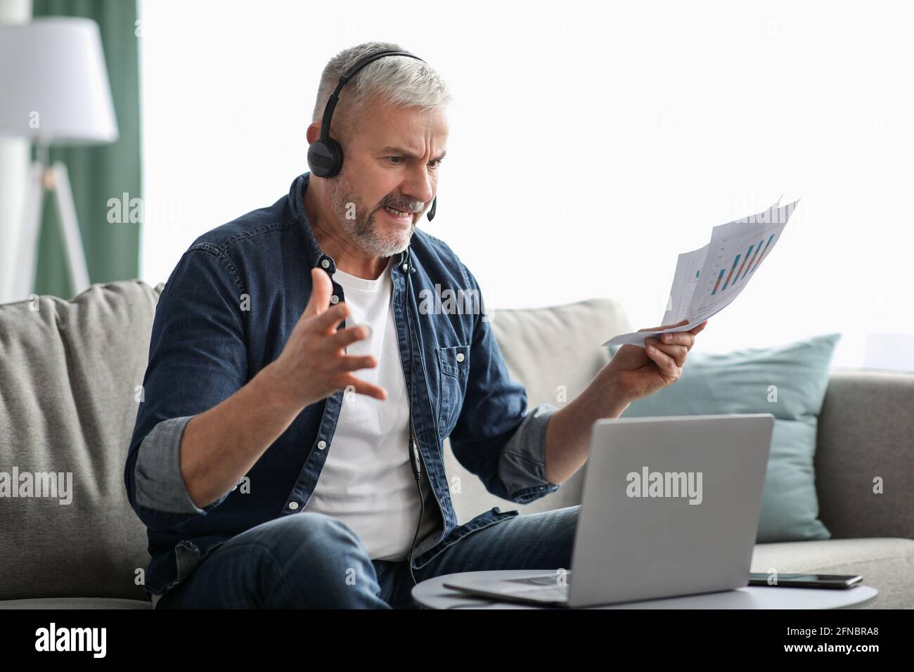 Furious senior businessman having video call with assistant Stock Photo