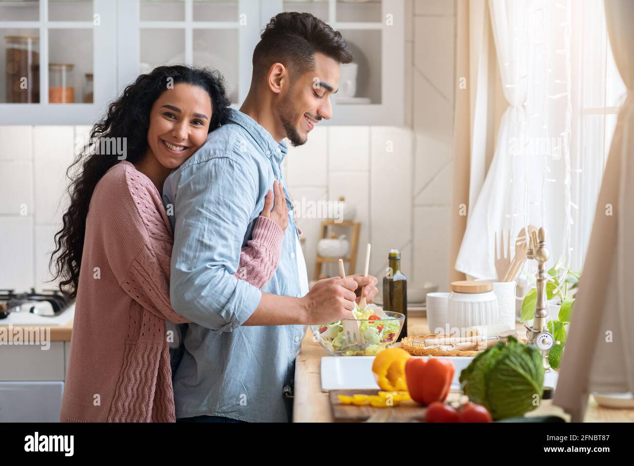 Portrait of loving arab wife embracing husband while cooking together in kitchen Stock Photo