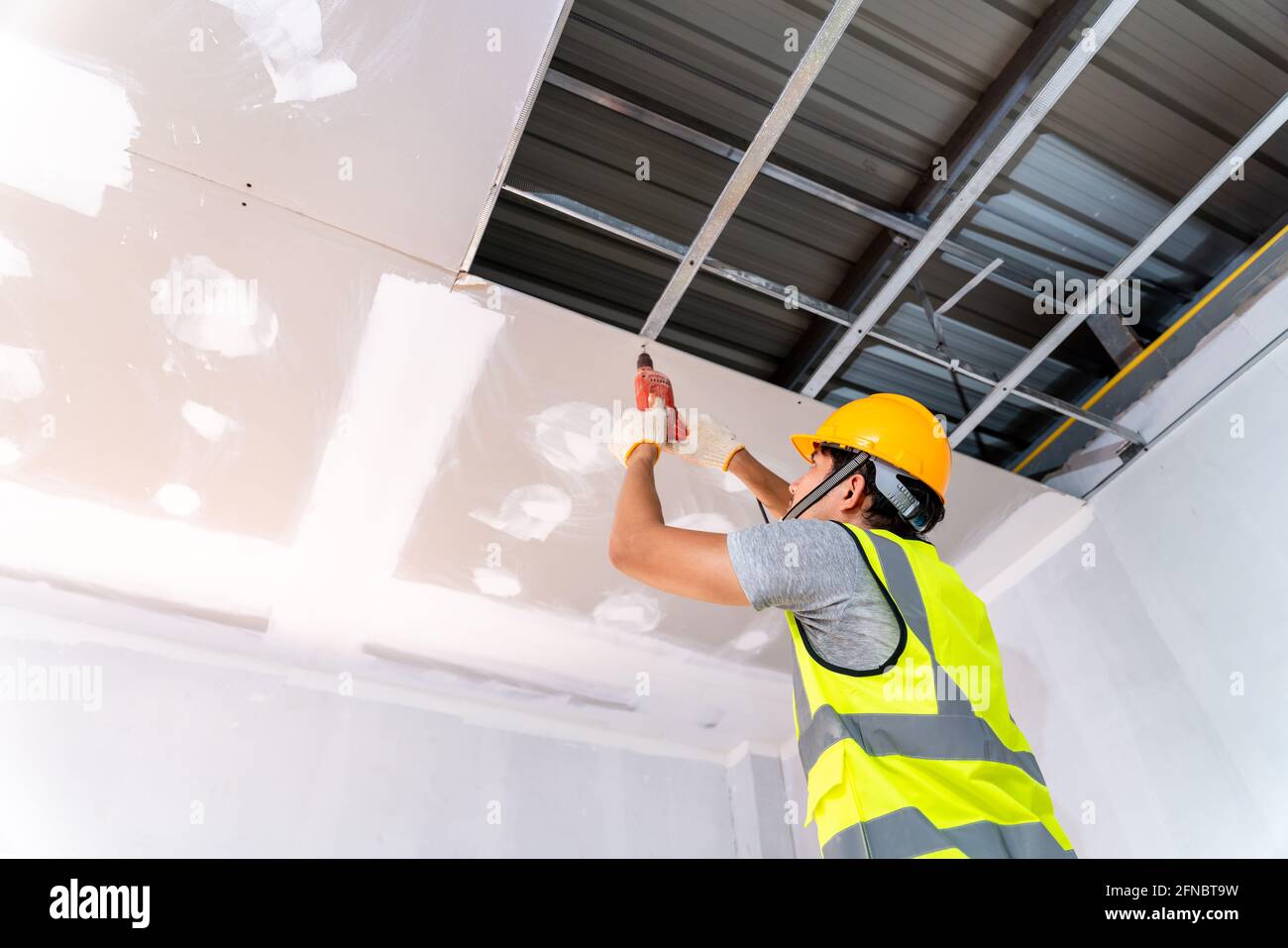 Construction workers using an electric drill are install the ceiling