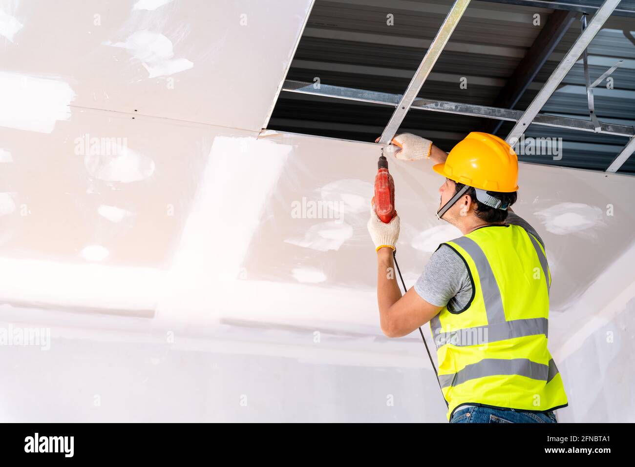 Construction workers using an electric drill are install the ceiling