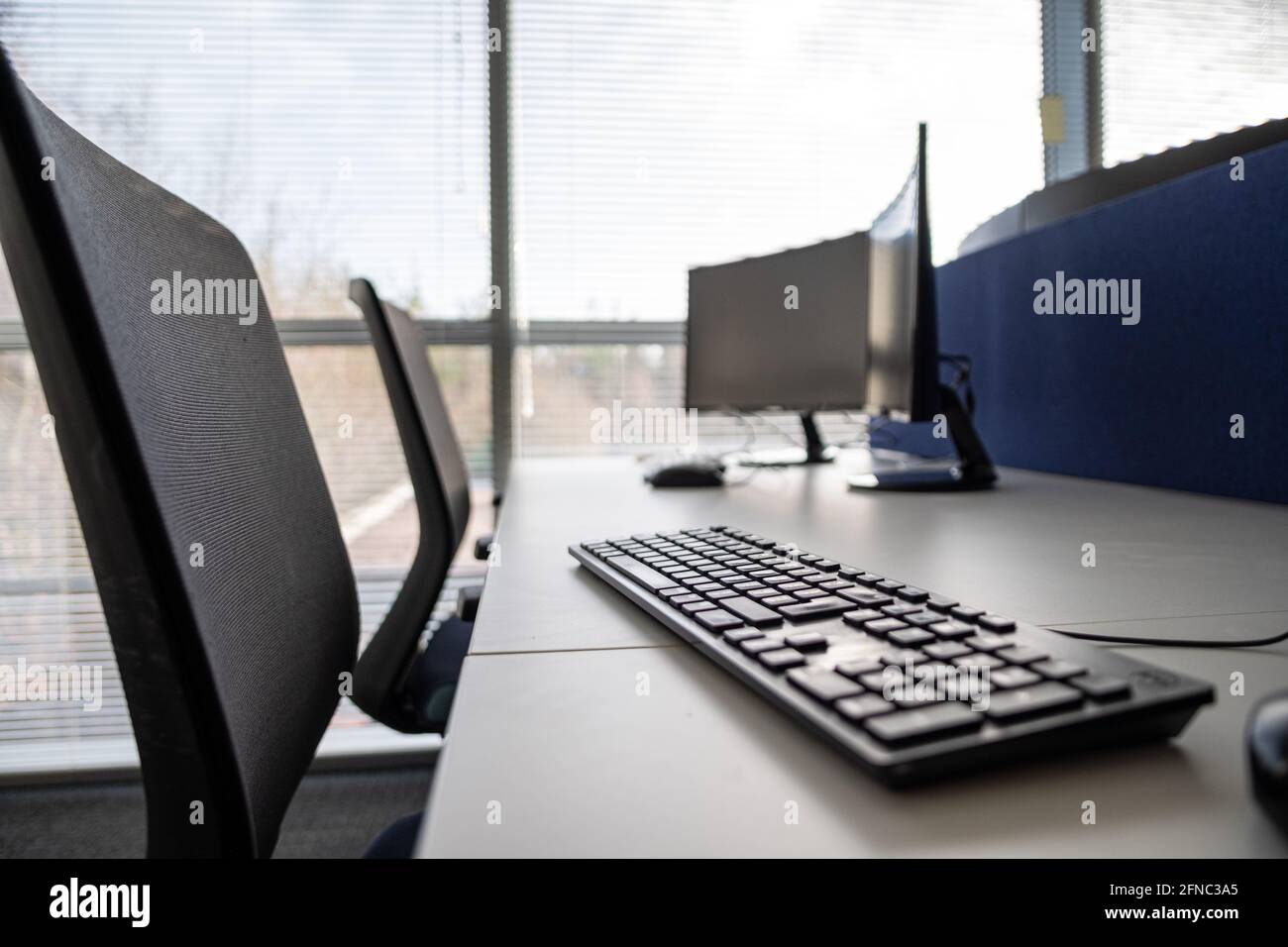 Chairs and dual monitors in an office, empty while people work from