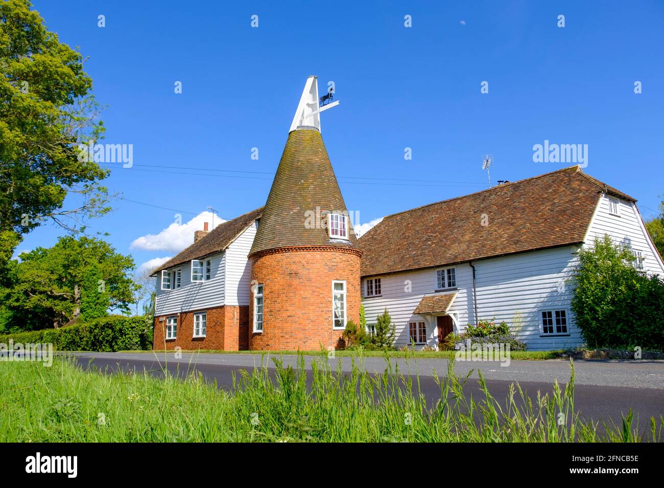 Traditional roadside Kentish Oast house and white clapboard house now converted into a home. Kent, England, UK Typical Kent scenery Stock Photo