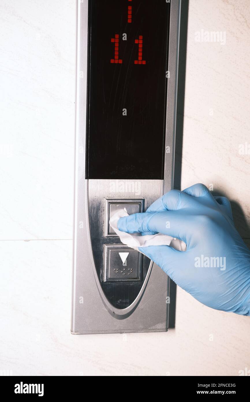 Man hand in protective gloves disinfecting elevator buttons. Stock Photo