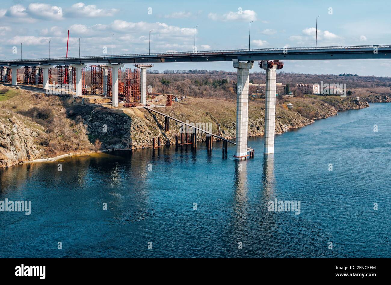 Construction of automobile bridge across the river. Industrial landscape. Stock Photo