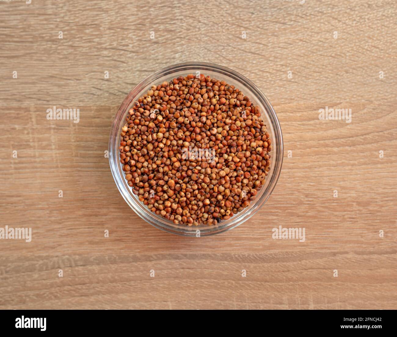 Bowl of raw sorghum grain on a wooden table Stock Photo