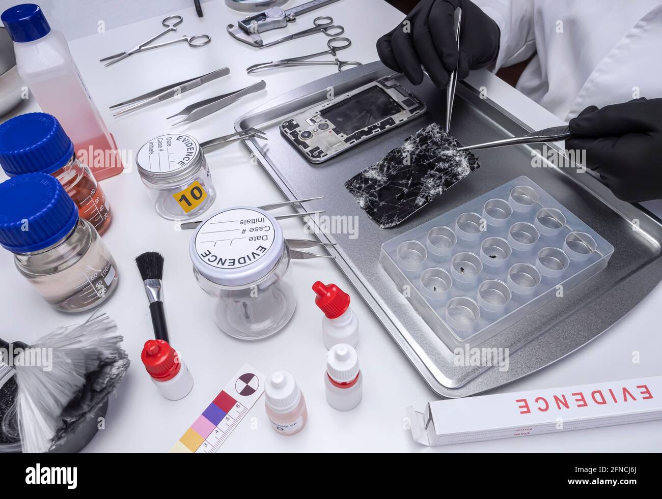 Specialized police investigate smartphone fragments in crime lab, conceptual image Stock Photo