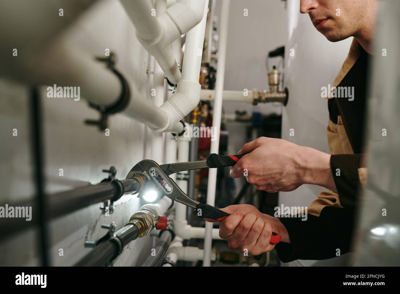 Repairman using a tool to fix parts of pipes during work Stock Photo