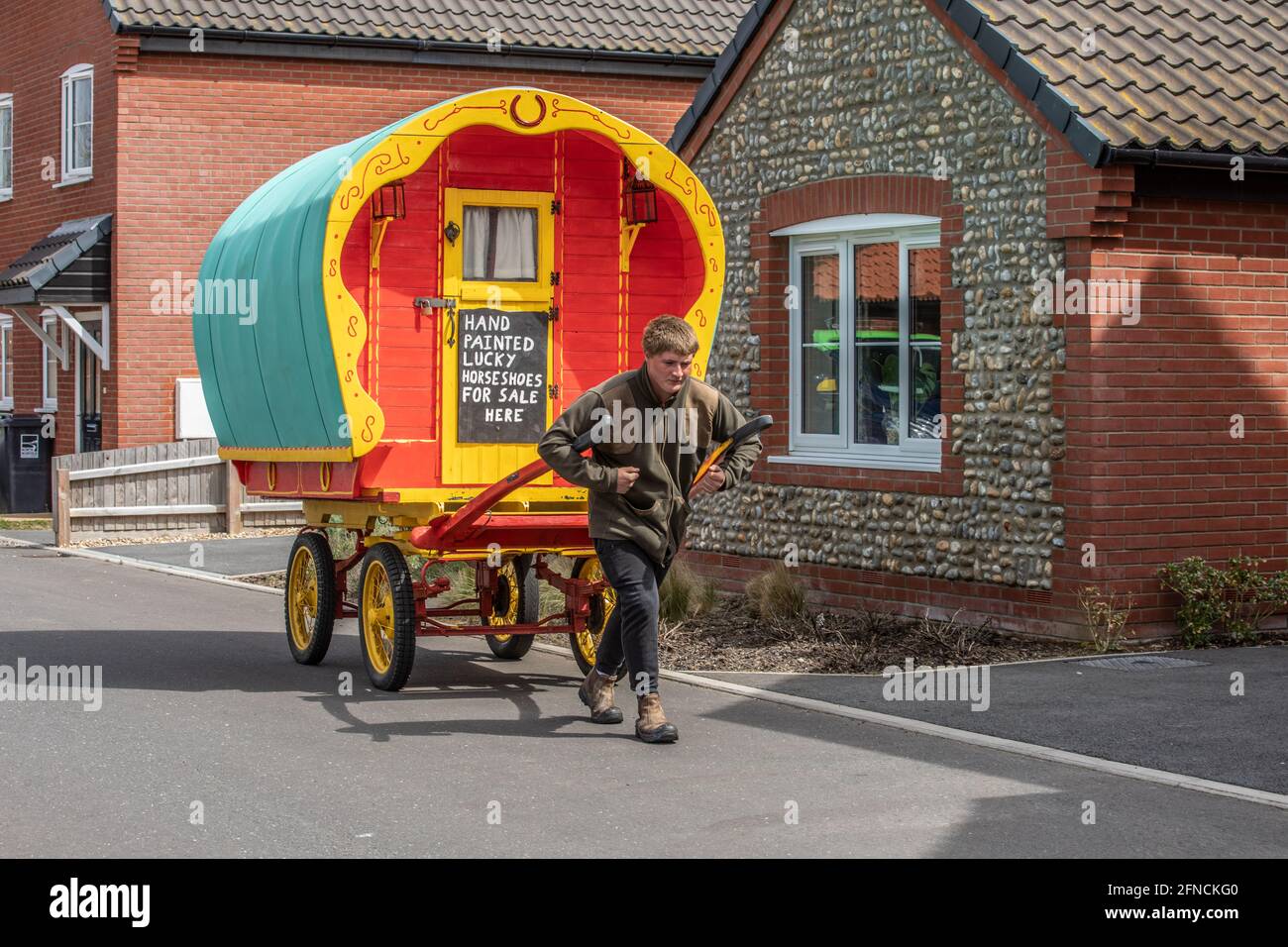 Freddy Coleman carries his antique horse cart looking for business selling painted horseshoes in Bacton, Norfolk, England, United Kingdom Stock Photo
