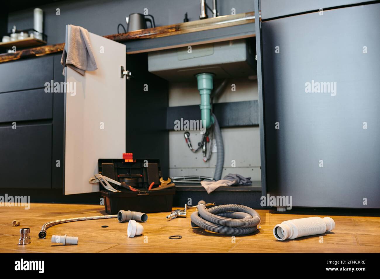 Open door of under sink in the kitchen, toolbox and plumbing