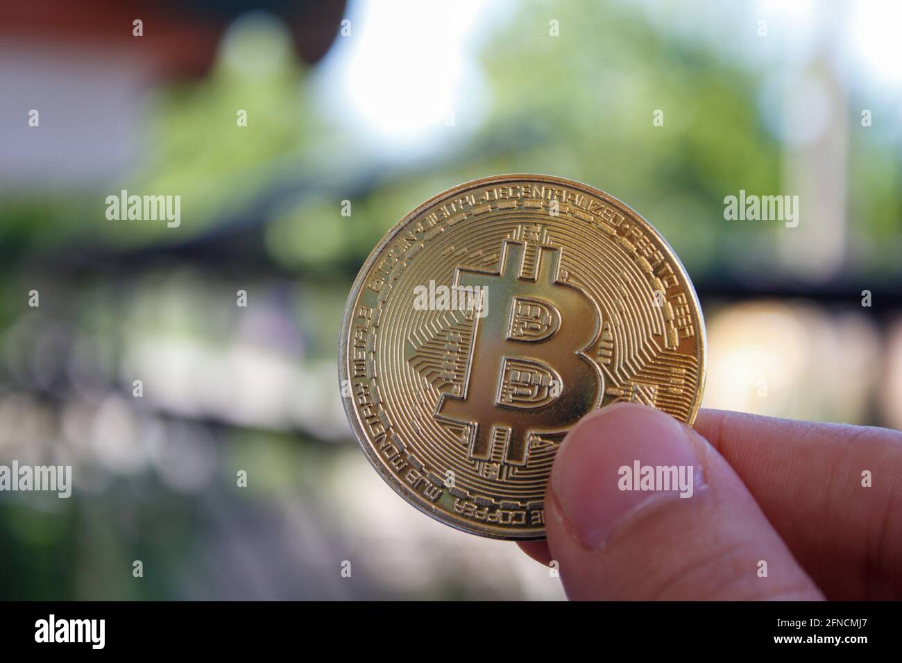Close-up virtual bitcoin coin in hand. Man hand holding golden btc coin. Bitcoin is popular cryptocurrency. Stock Photo