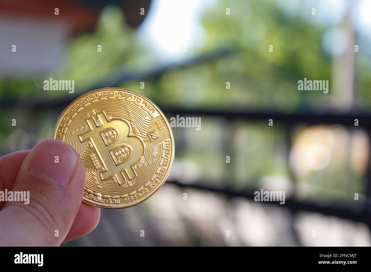 Close-up virtual bitcoin coin in hand. Man hand holding golden btc coin. Bitcoin is popular cryptocurrency. Stock Photo