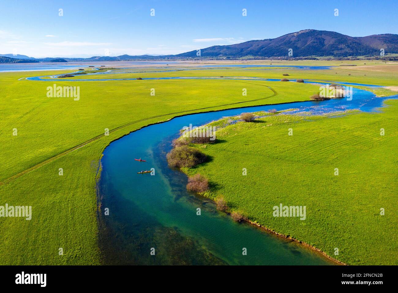 Top aerial view of two kayaks in tributary that flows into Cerknica Lake, beautiful view over the lake and mountains, taken by drone, Slovenia Stock Photo