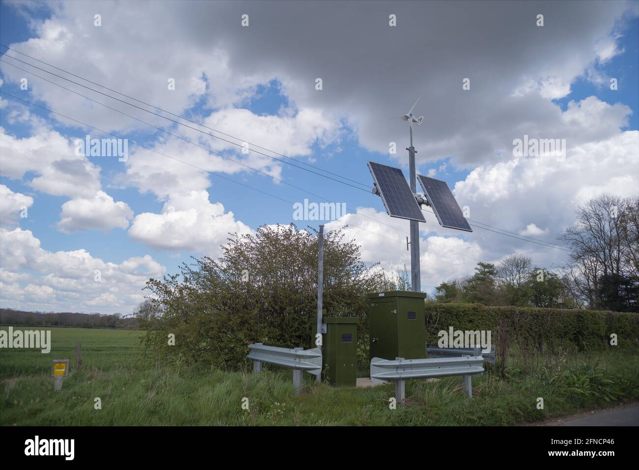 Small wind turbine protected from traffic on isolated country lane monitoring a gas substation distribution point Stock Photo