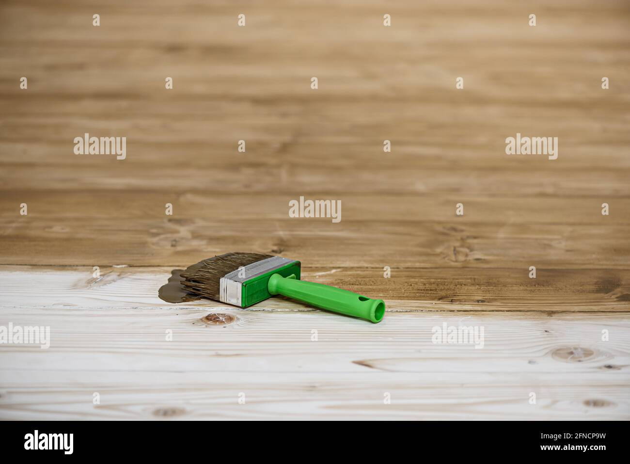 Square cut brush on wooden floor. Toning floor with stain, texture enhancement. Decoration