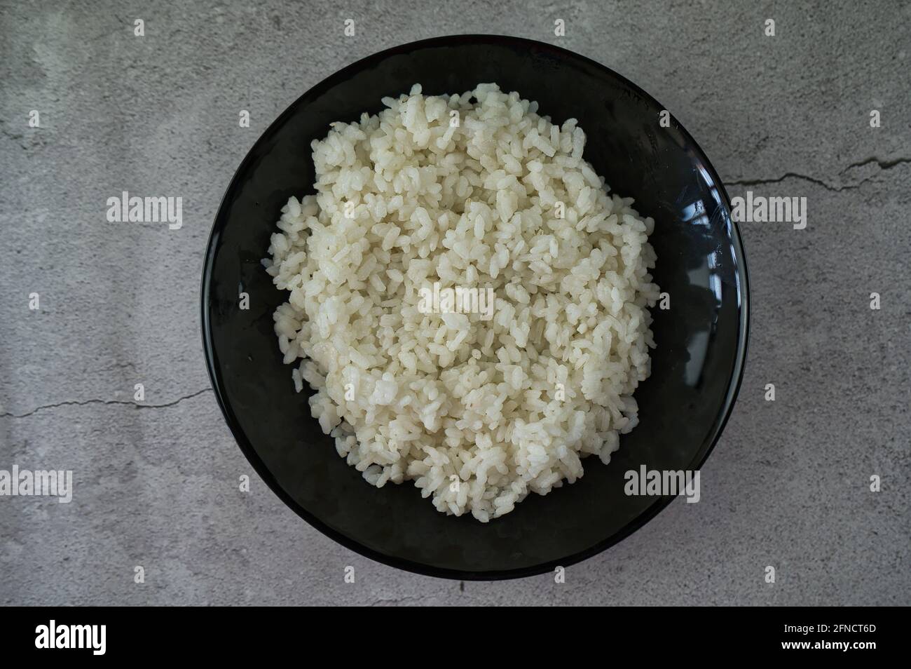 black plate with cooked rice on the table. food Stock Photo - Alamy
