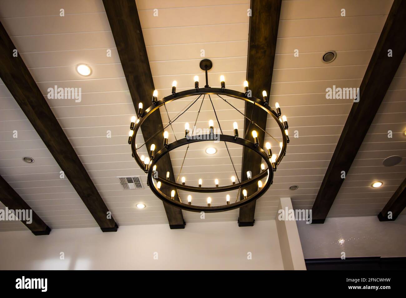Two Tier Chandelier Hanging From Exposed Beam Ceiling Stock Photo