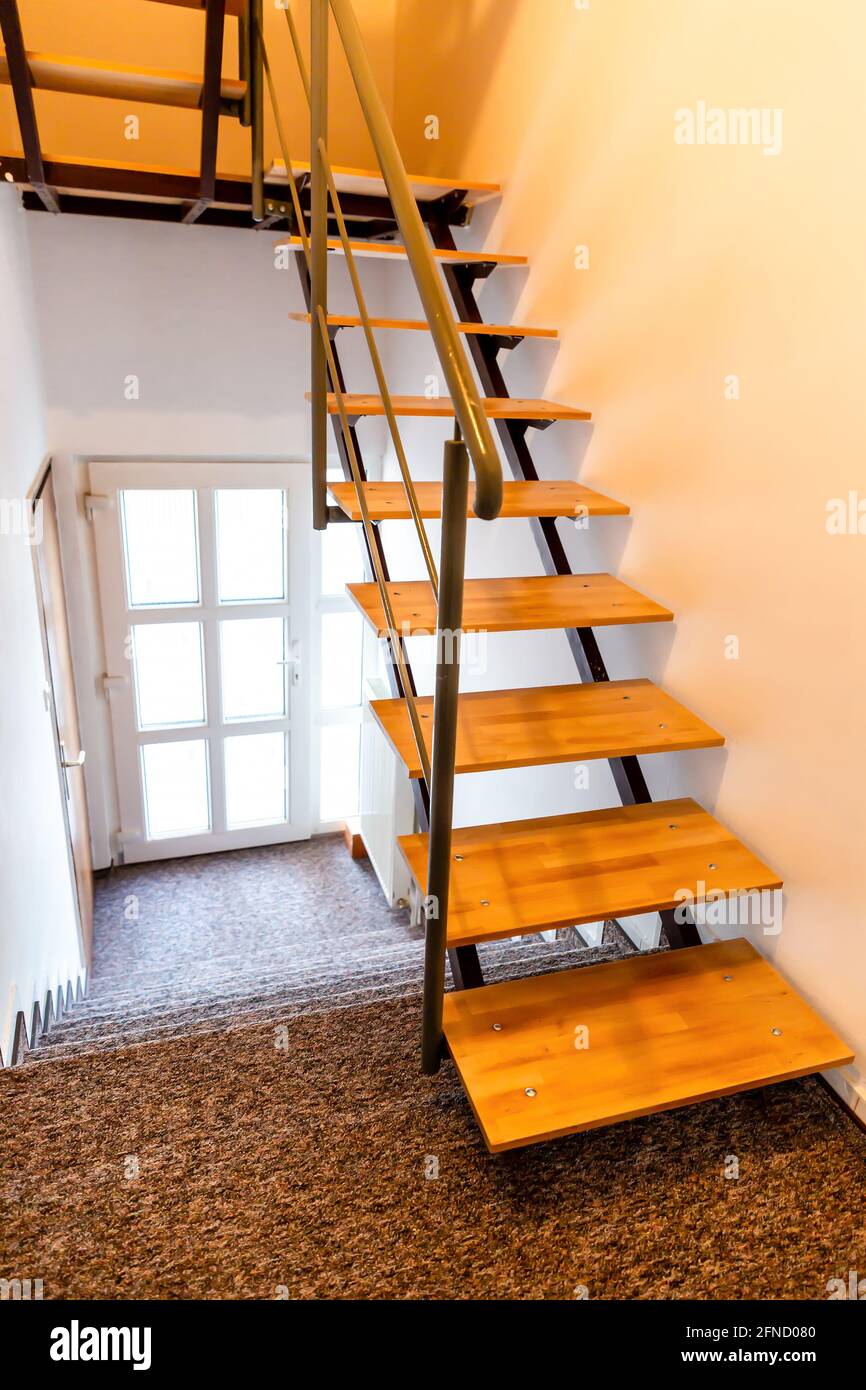 Staircase inside residential building. One part covered with brown carpet, other part made of natural wood. Stock Photo