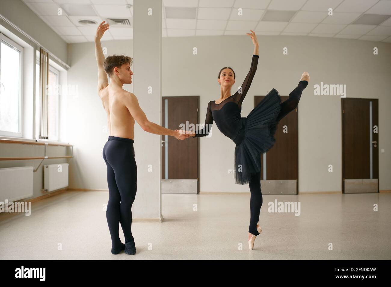 Female and male ballet dancers dancing at barre Stock Photo