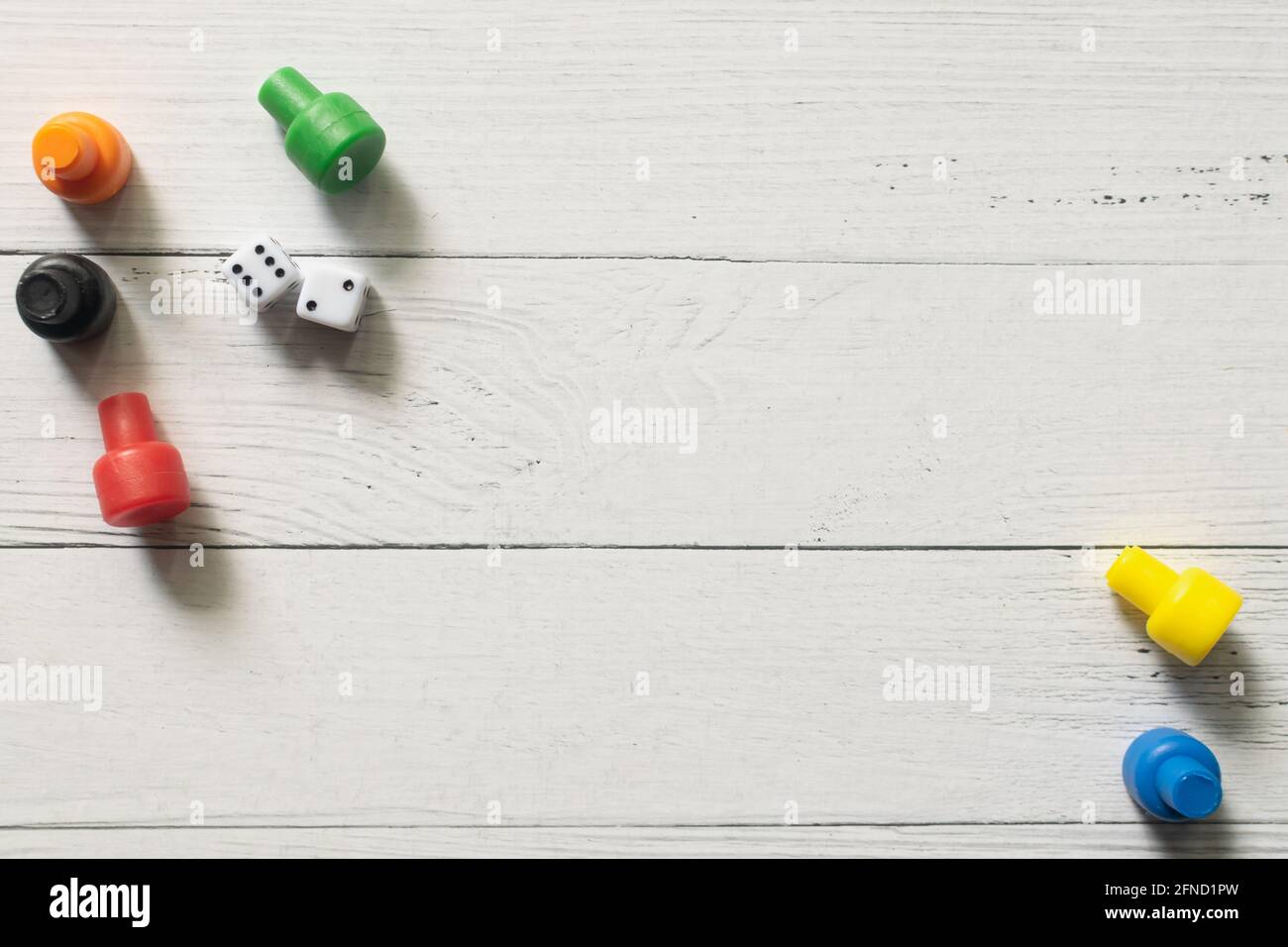 Multi-colored game chips with dices on wooden board. Board game. Stock Photo
