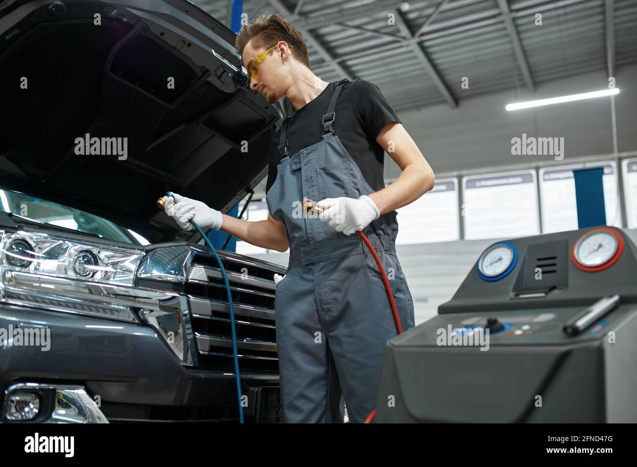 Male mechanic refills air conditioner, car service Stock Photo Alamy