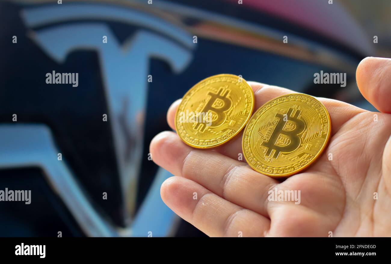 Calgary, Alberta, Canada. May 14, 2021. A person holding a couple bitcoin  with the Tesla car on the background Stock Photo - Alamy