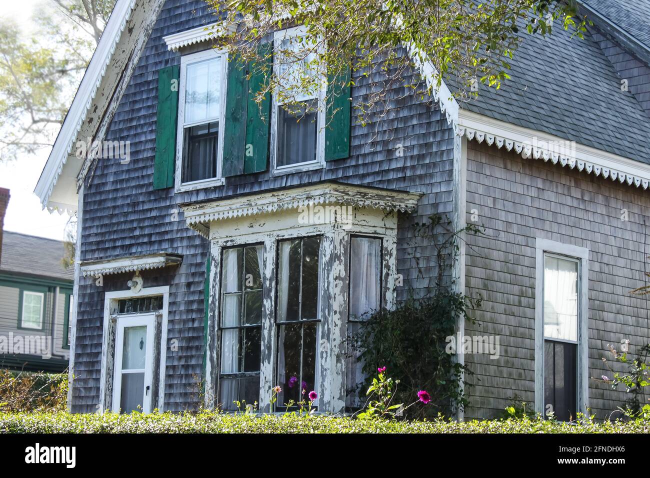 Weathered clapboard Cape Cod house with bay window and green shutters Stock Photo