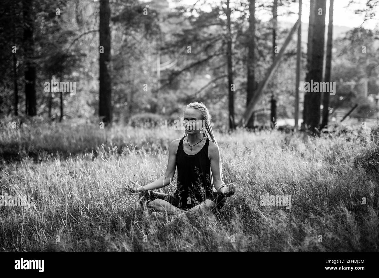 A yoga woman sit in lotos pose in the forest. Black and white photo. Stock Photo